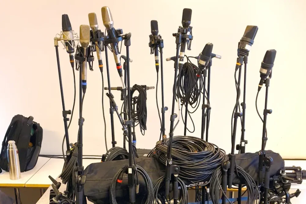 Cybele Studio on the road – during a DSD live production in the main hall of De Doelen (Rotterdam): an array of studio microphones on stands, with coiled cables and flight cases between them