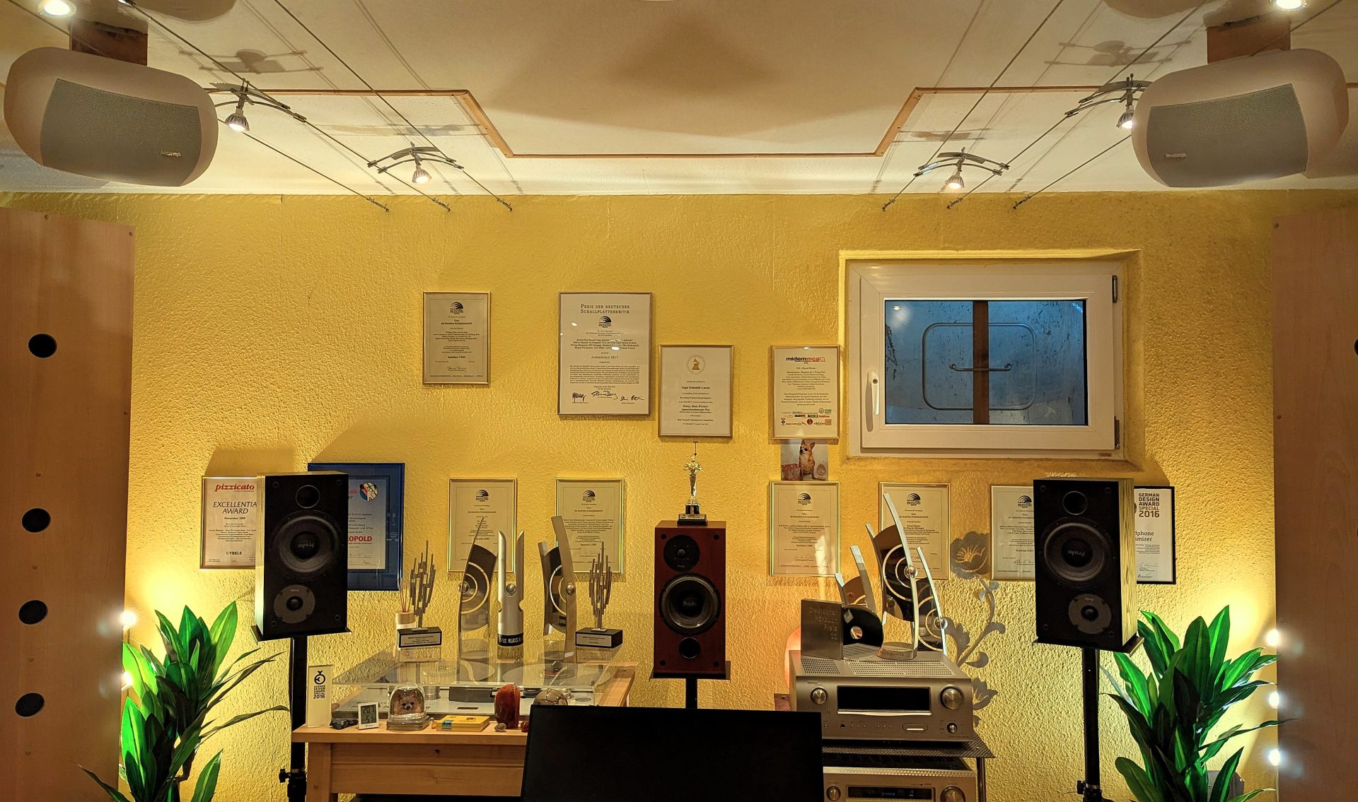 Inside the Cybele Studio – control room with black ProAc 100 studio monitors, a red-brown ProAc centre speaker and white ceiling speakers for the Dolby Atmos upper layer; numerous record awards behind (Grammy nomination, MIDEM Classical Awards, ECHO Klassik, German Audiobook Award and OPUS KLASSIK)